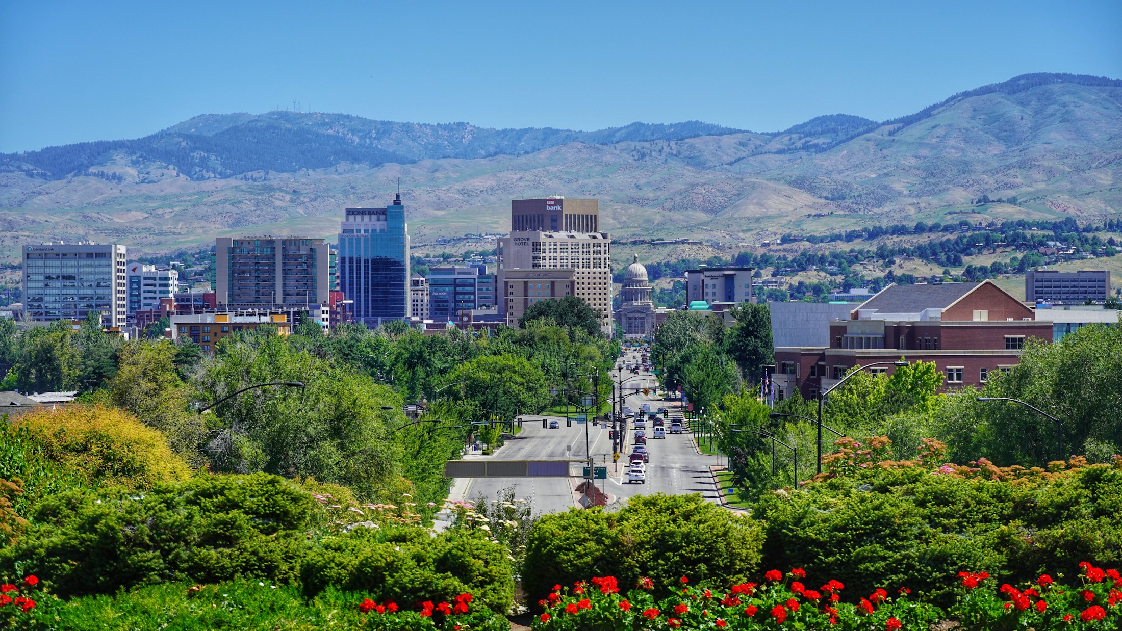 Downtown Boise framed by green trees, flowers, and the foothills